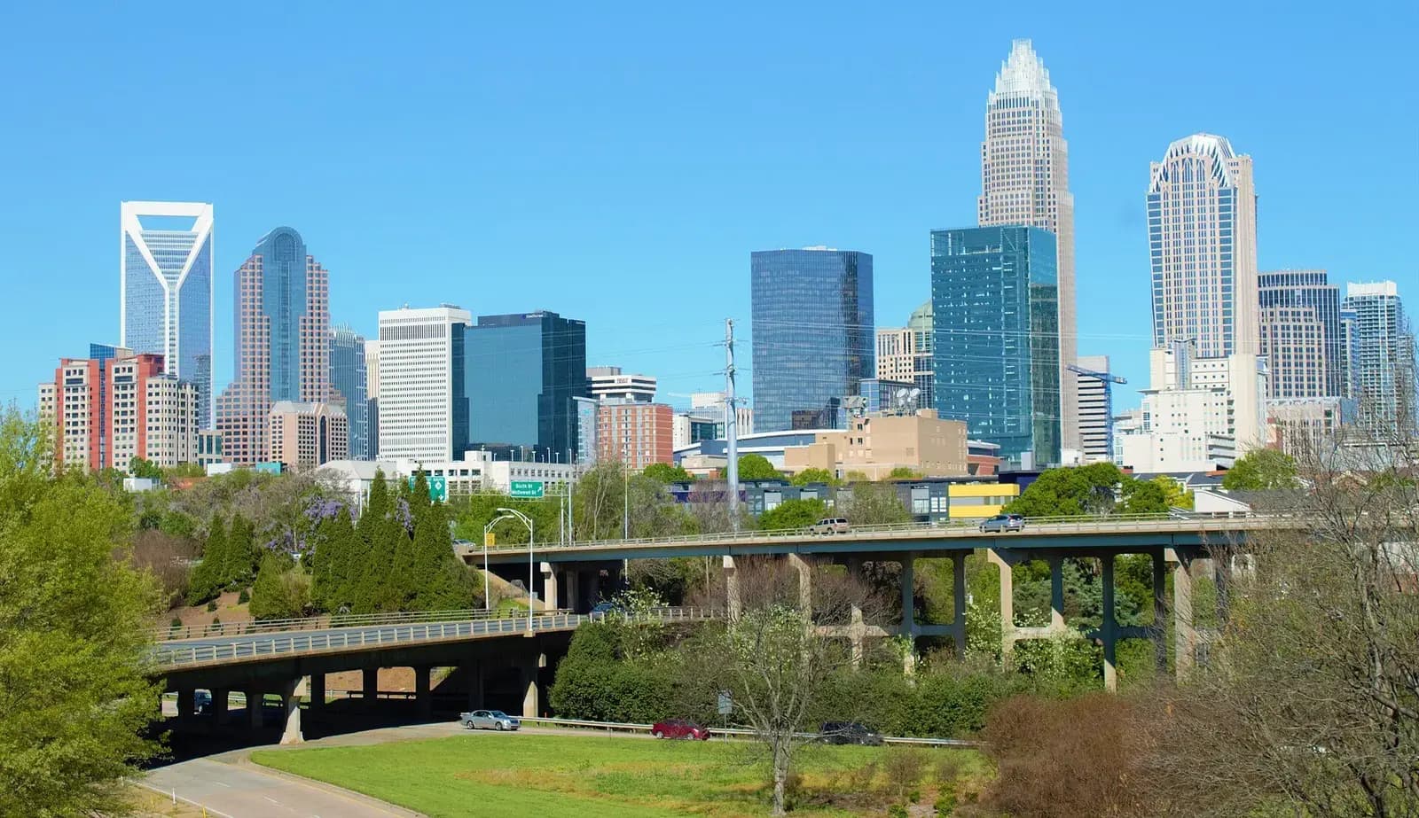 Uptown Charlotte skyline rising above green trees on a clear day