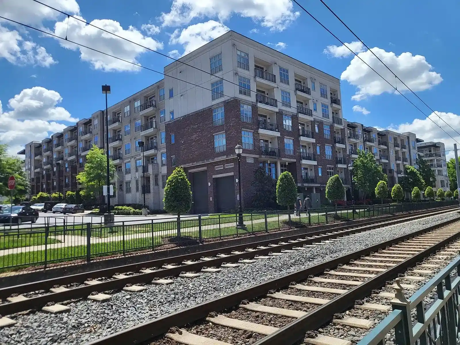 Mid-rise building along the Rail Trail in Charlotte, seen across the light rail tracks