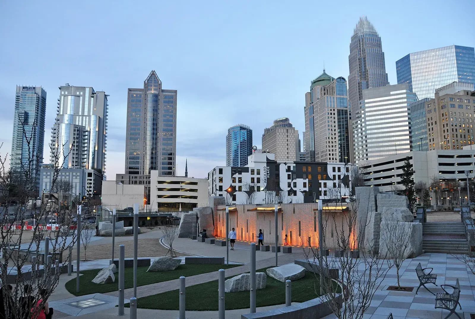 Uptown Charlotte towers above a landscaped plaza at dusk