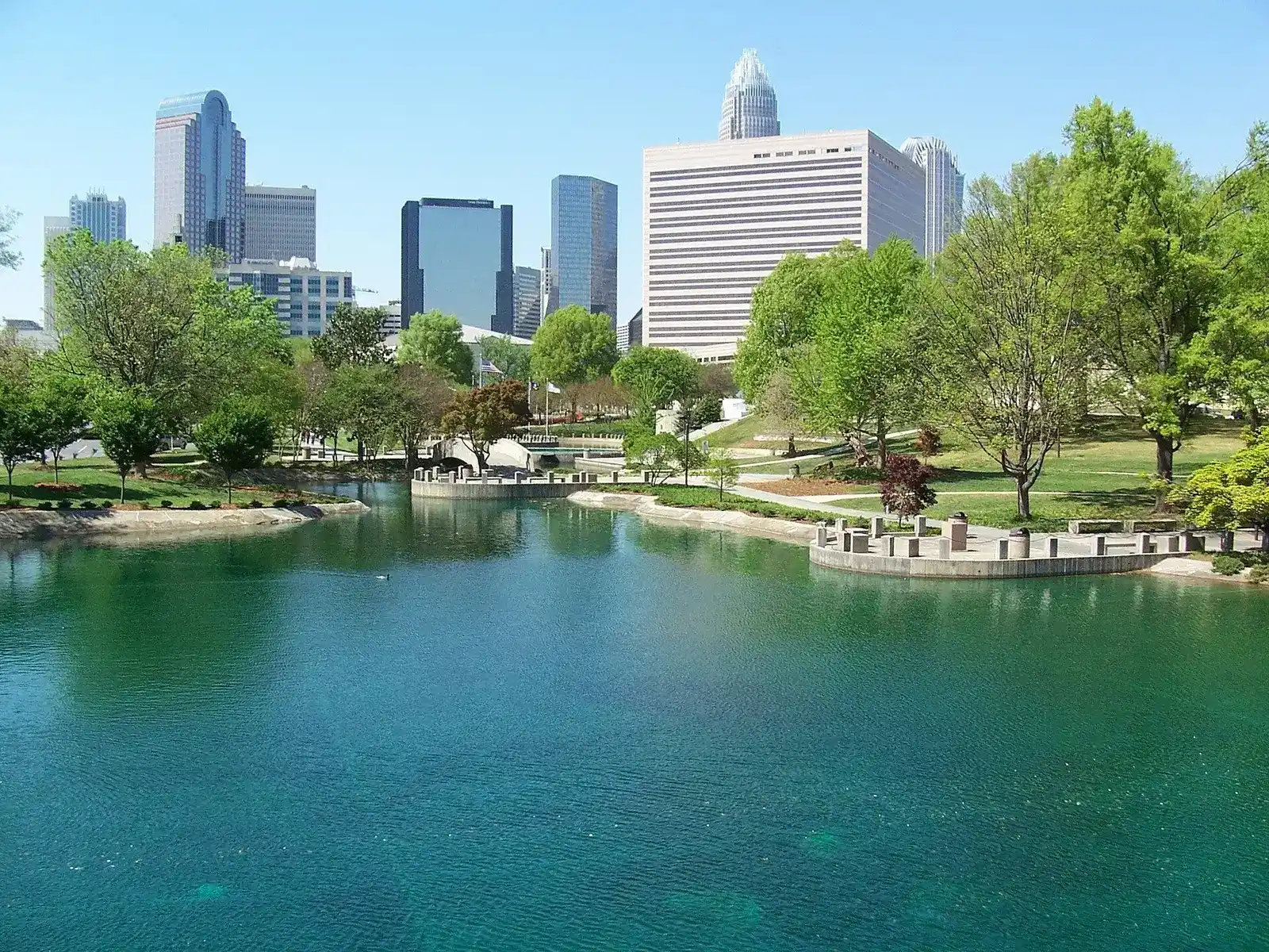Pond and green lawn at Marshall Park with Uptown Charlotte towers behind