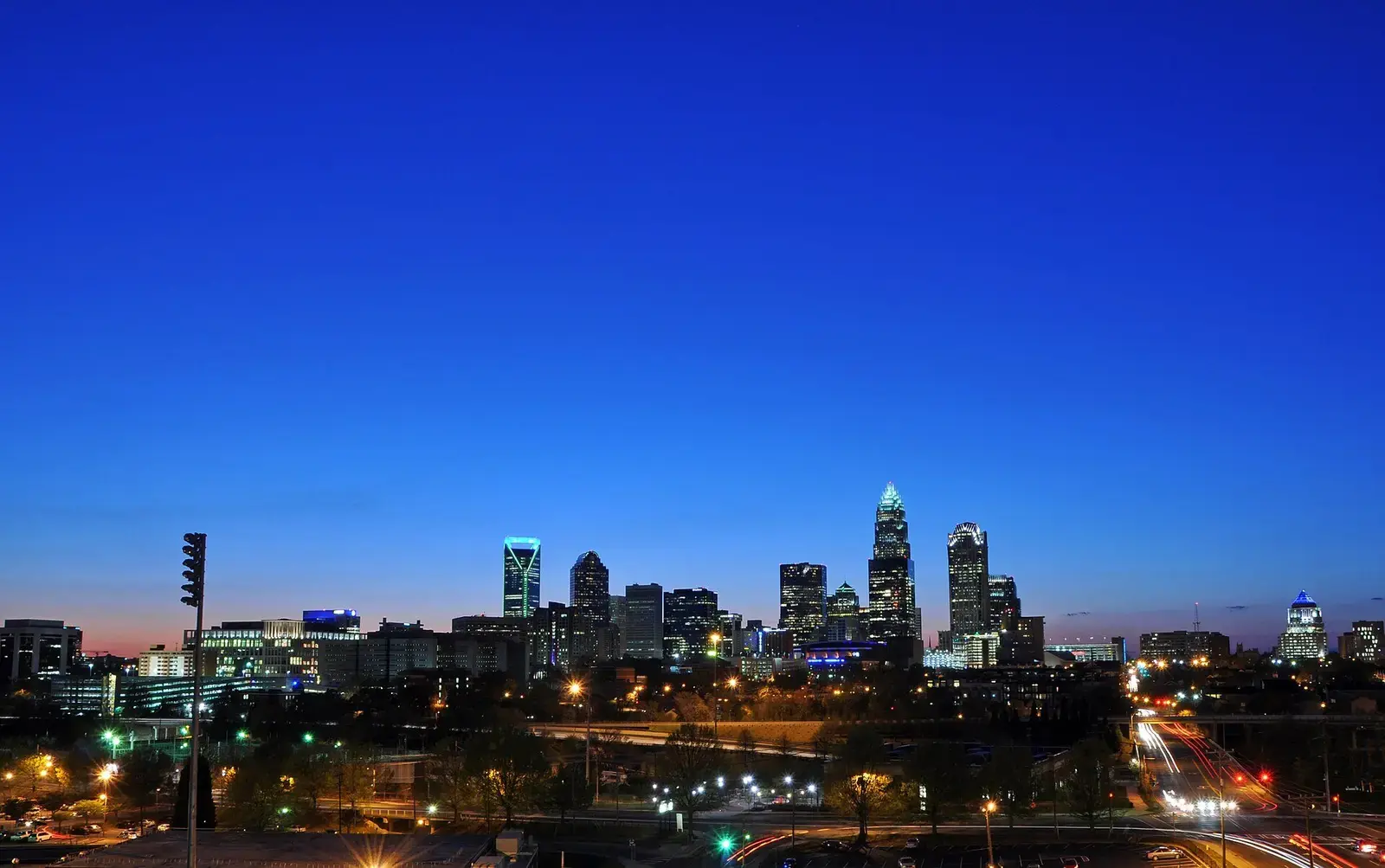 Charlotte skyline at dusk with lights reflecting across the city