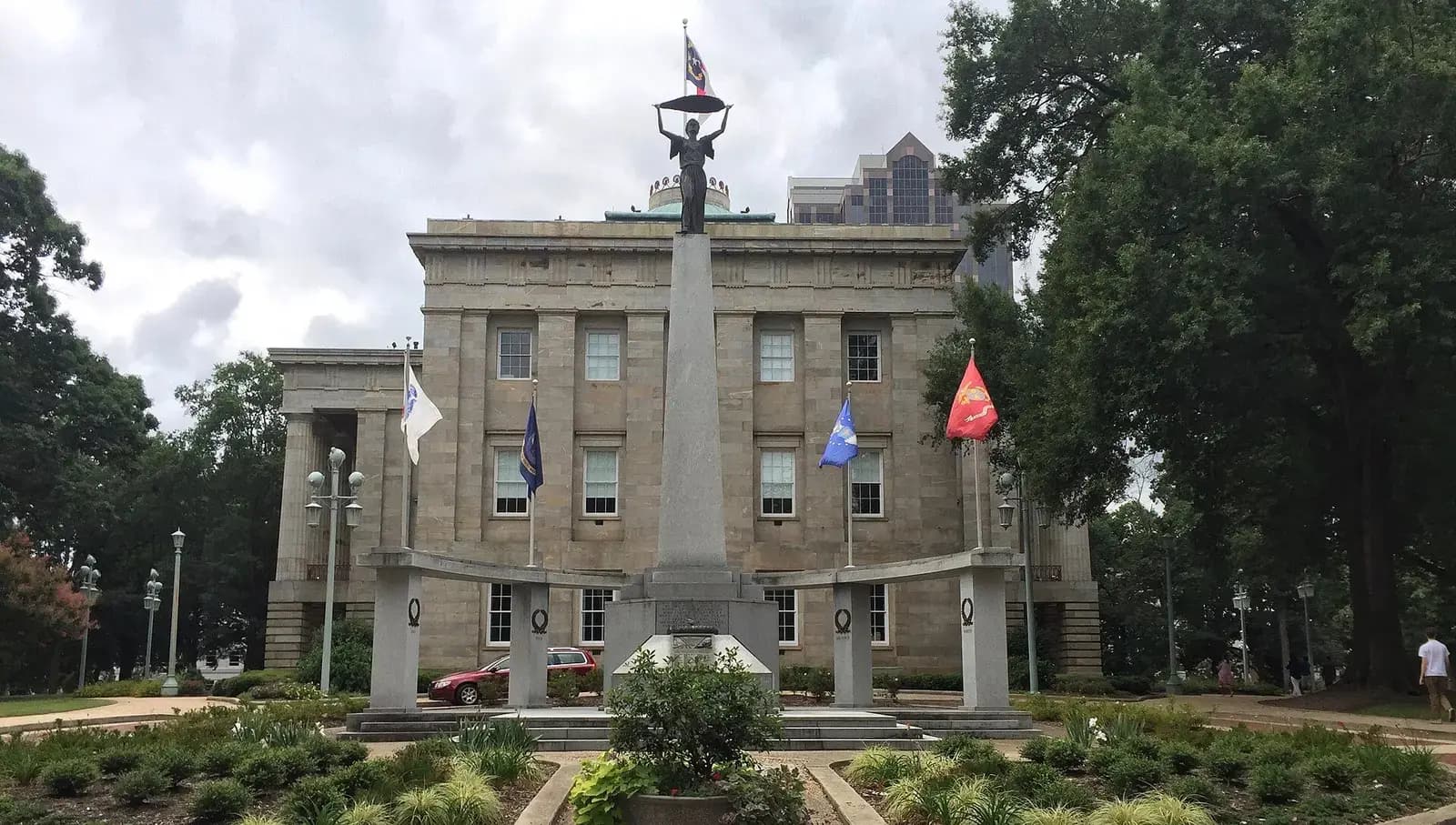 North Carolina State Capitol with monument and flags in Raleigh